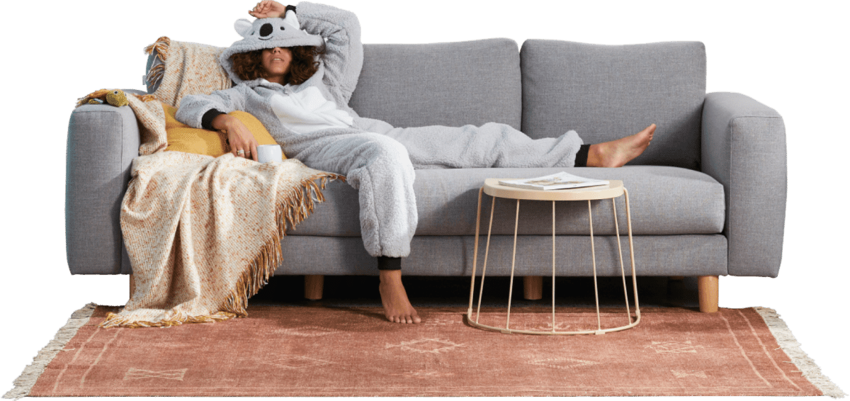 A woman in a koala onesie slouching on a couch