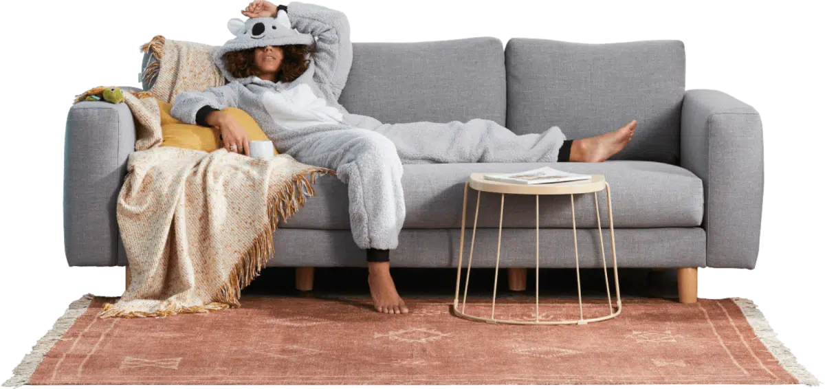 A woman in a koala onesie slouching on a couch