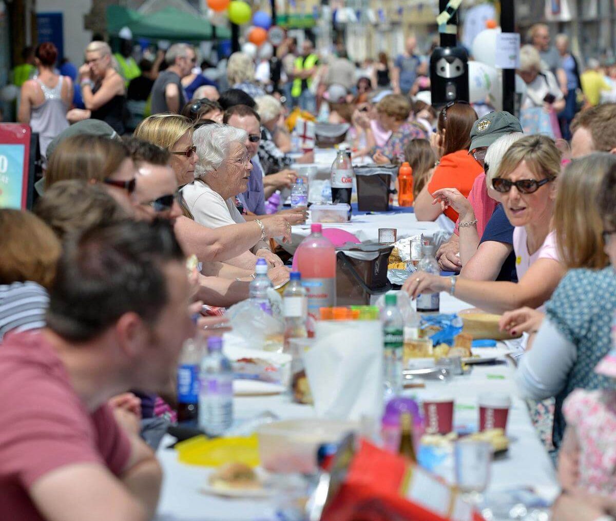 People sharing a long table at a festival