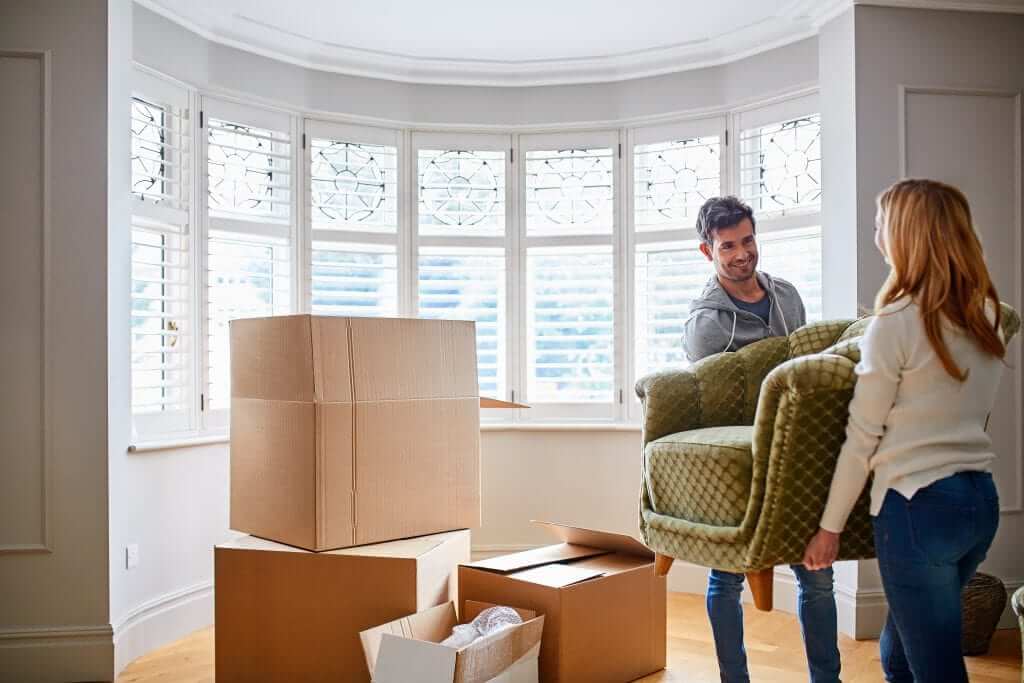 A couple helping each other lift the couch during a move