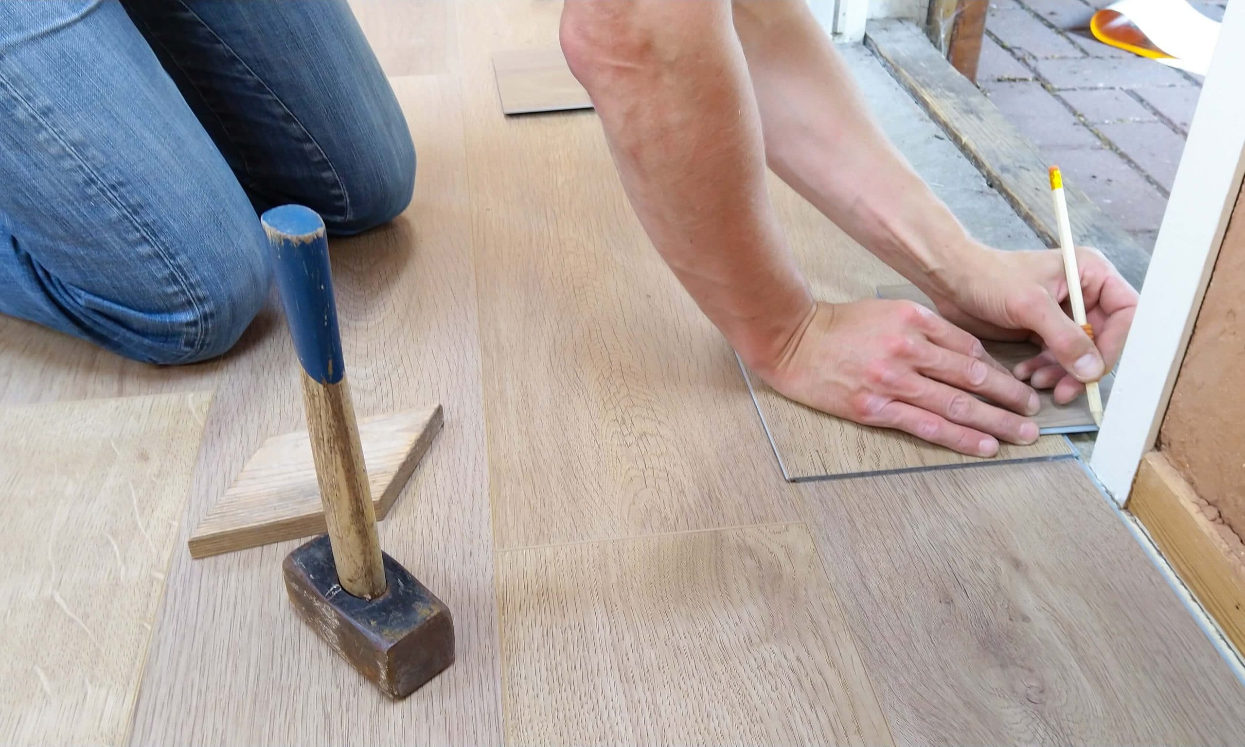 A handyman marking the wooden tiles with a pencil