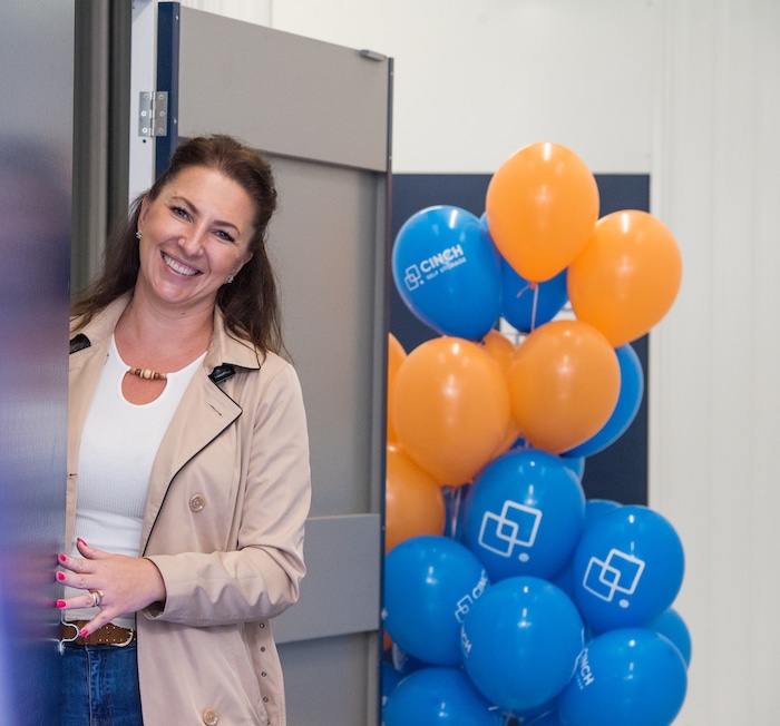 A woman standing at the entrace of a storage unit with a bunch of balloons behind her