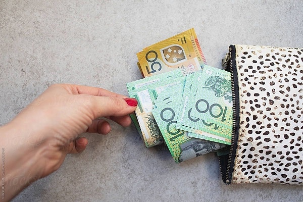 A woman pulling out Australian bills from a wallet