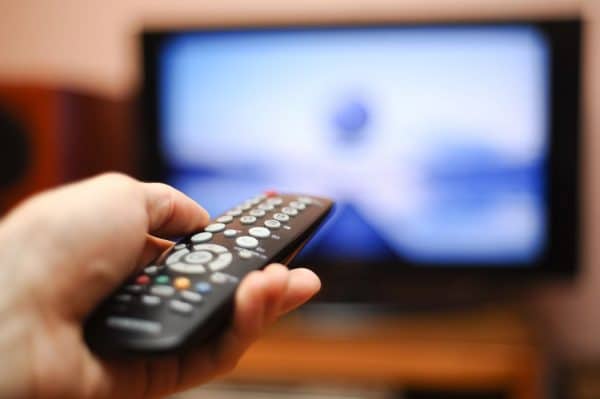 A person pointing a remote control at the TV