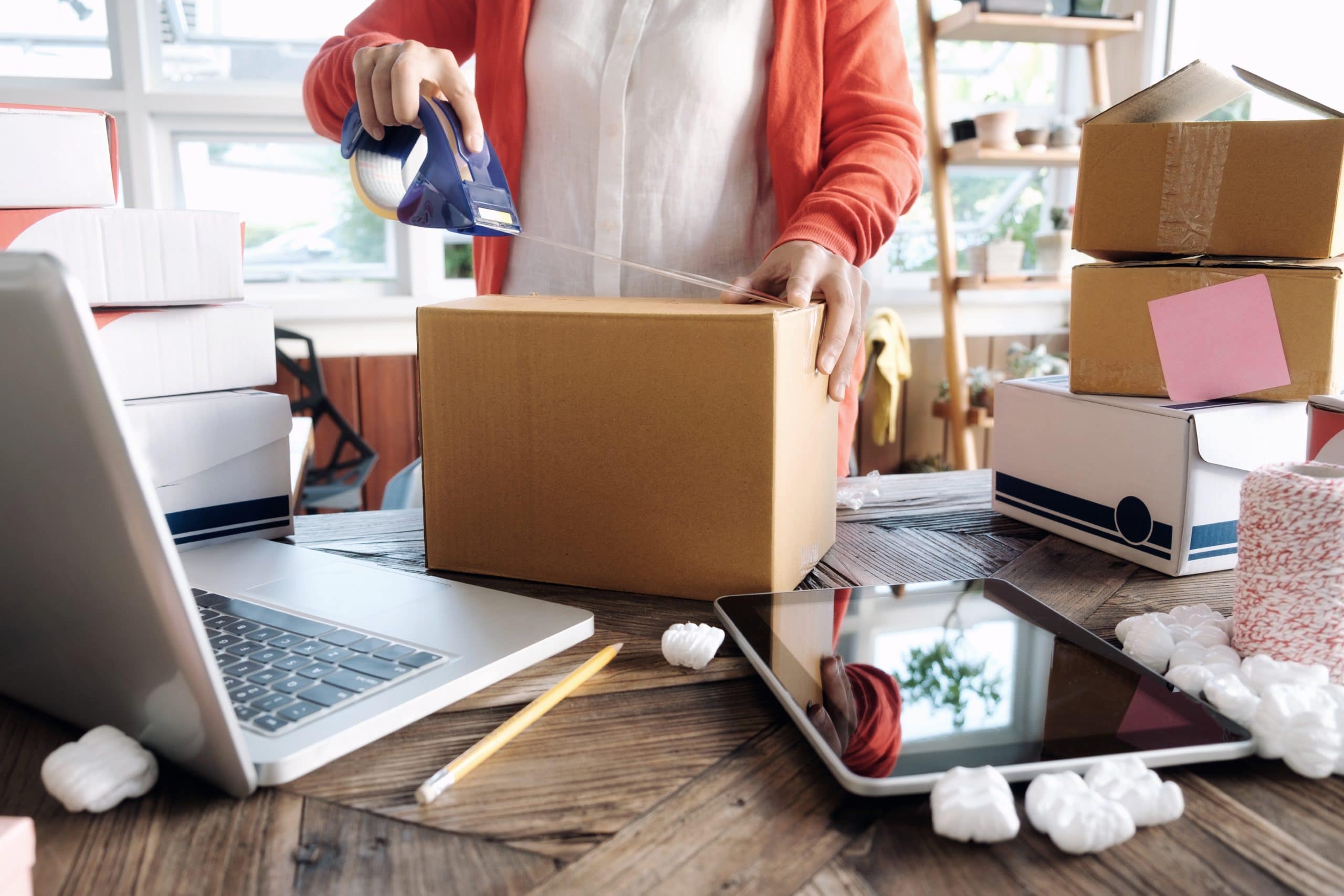 Woman packaging business storage at desk with laptop