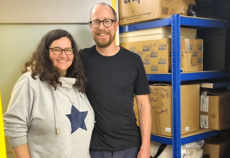 Man and woman standing in front of storage unit filled with shelves and boxes