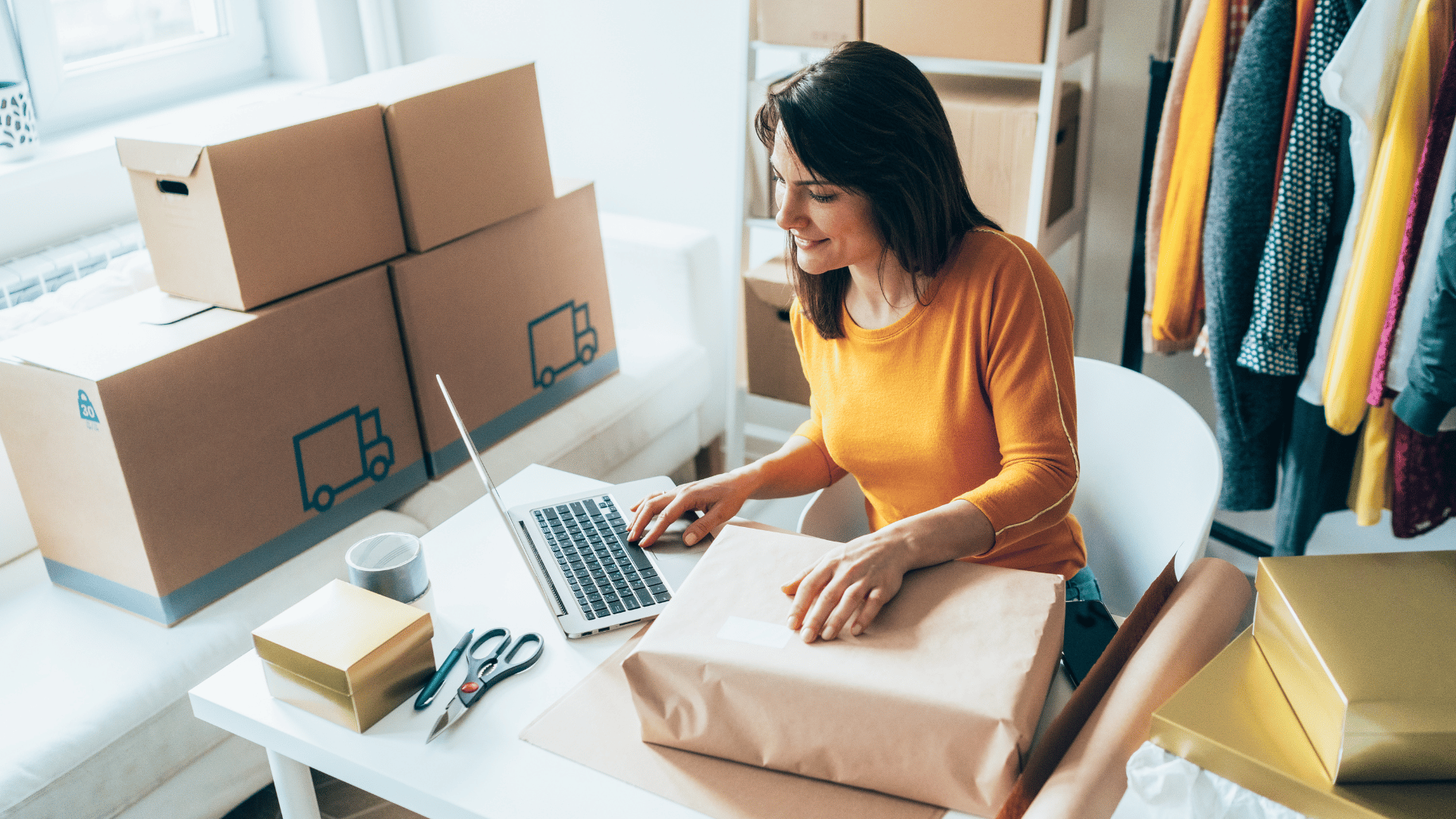 Woman working at desk surrounded by business storage boxes and clothes