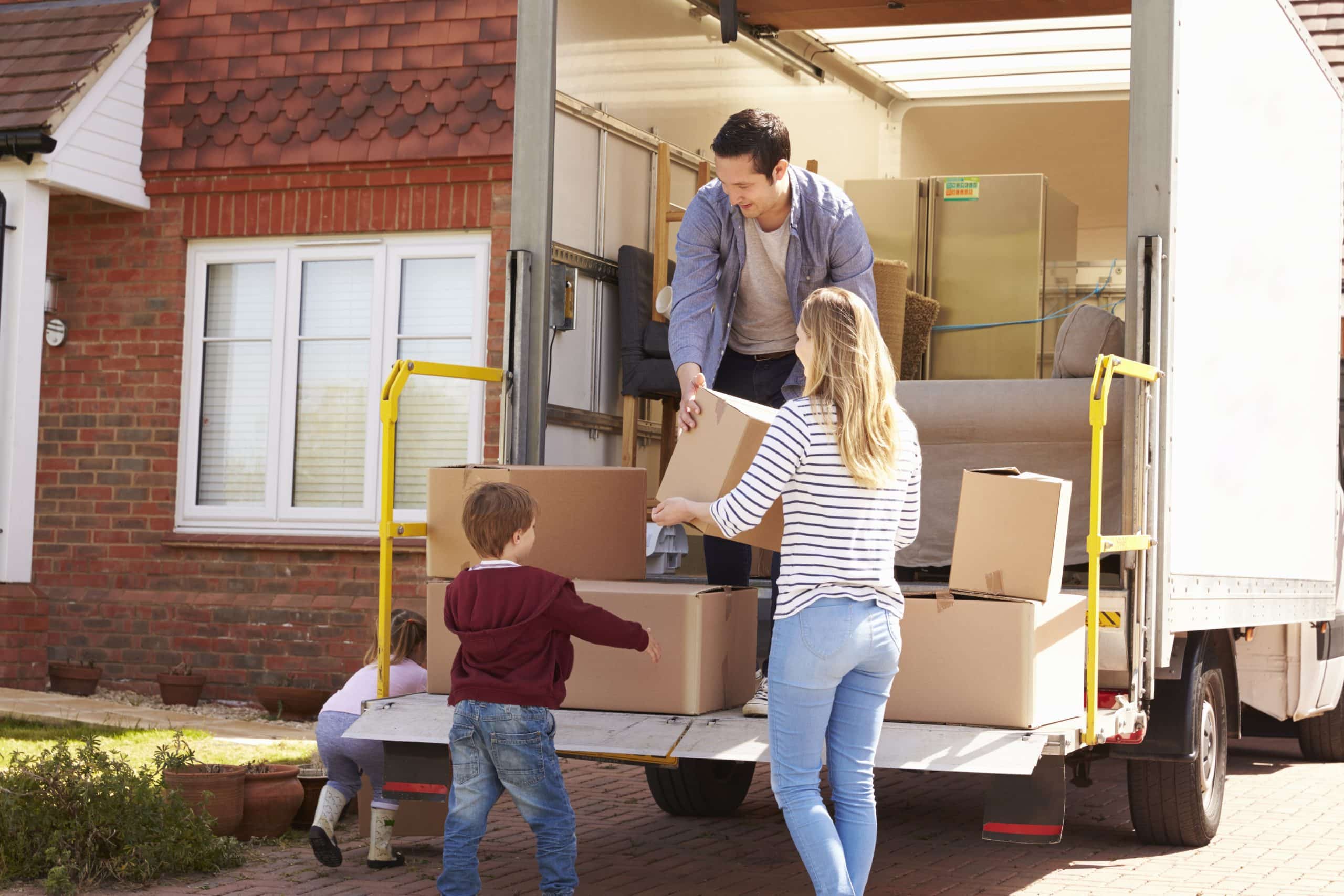 Family unpacking from a moving van parked in front of new home