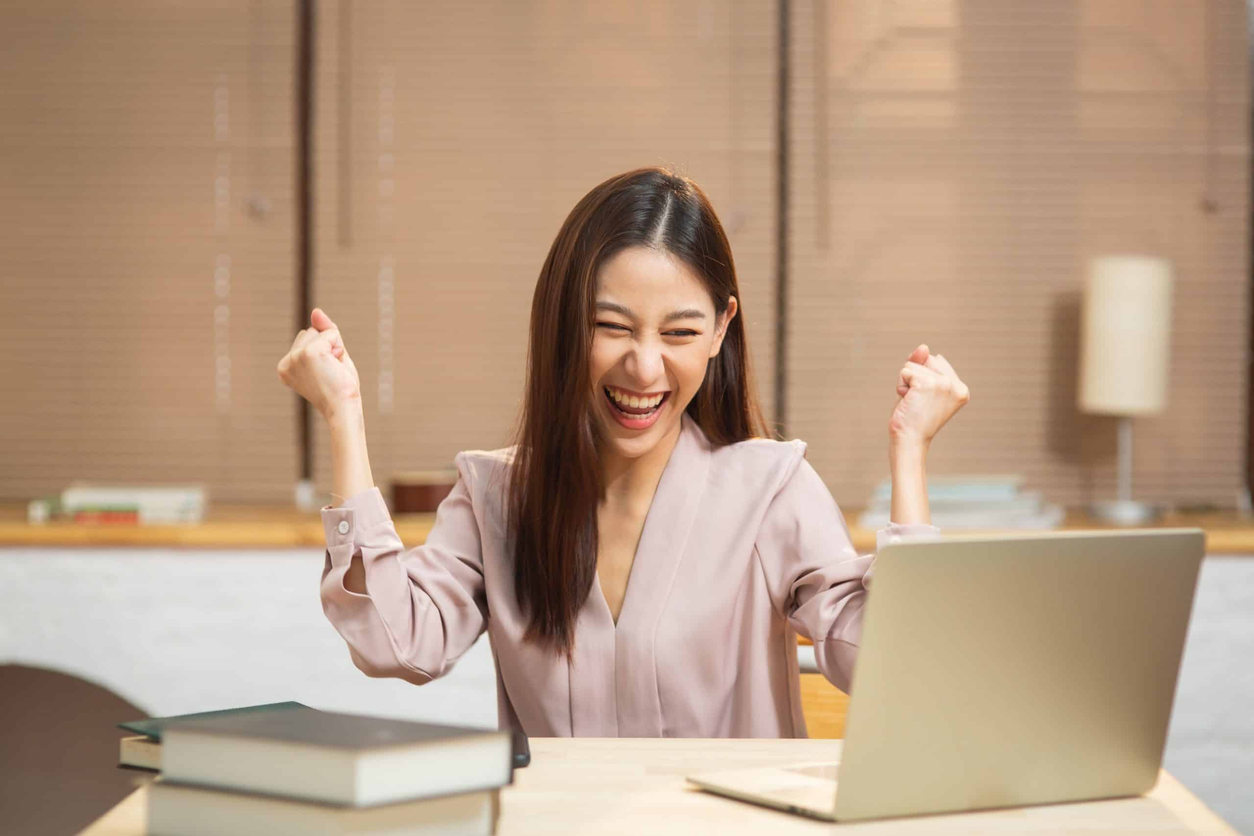 Young woman celebrating at her laptop in her office Space in Calne