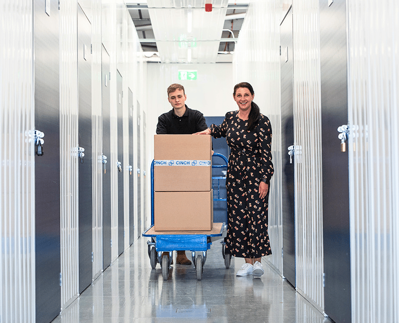 Storage to rent Chingford - corridor of storage units with two people pushing a trolley with boxes on