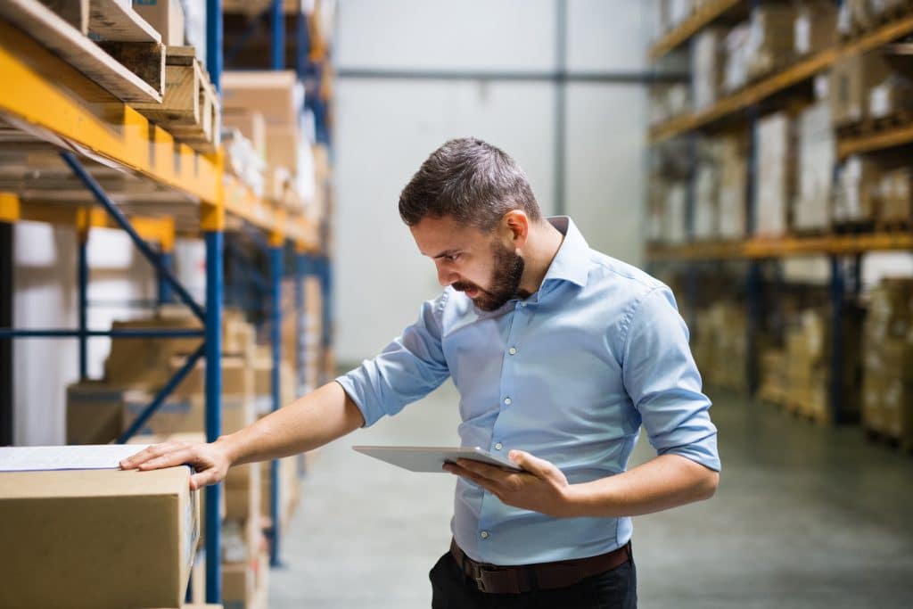 Industrial units to rent Huntingdon - man inspecting boxes on a shelf holding a tablet 