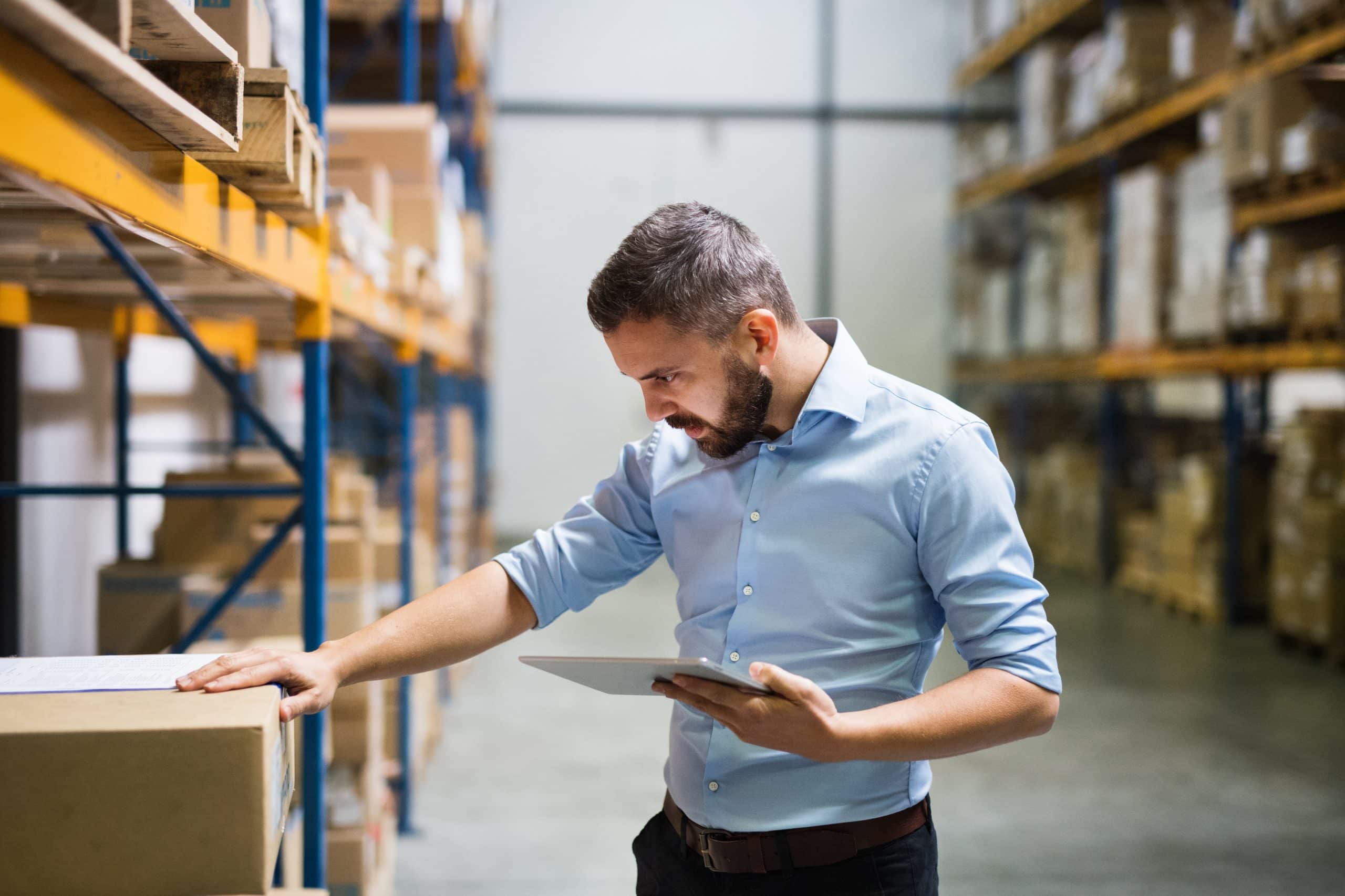 Industrial units to rent Huntingdon - man inspecting boxes on a shelf holding a tablet