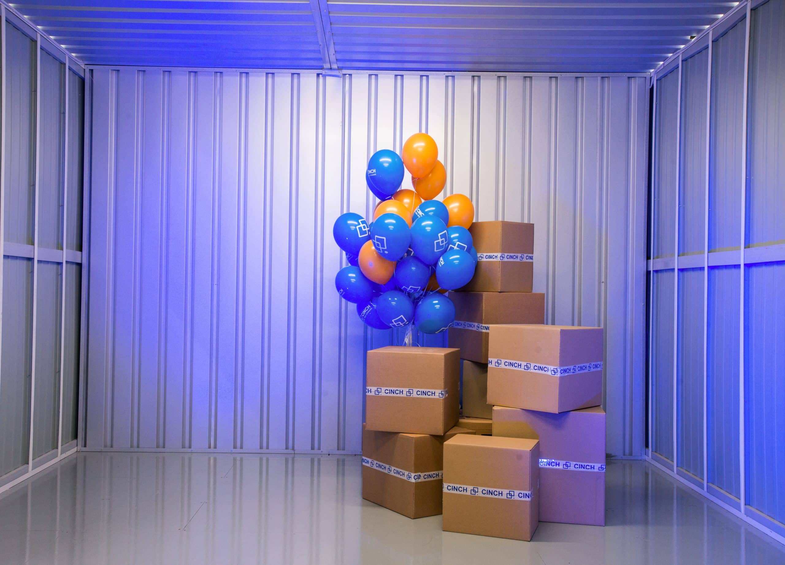 Newbury storage units - photo showing the inside of a storage unit with cardboard boxes and blue and orange balloons, with blue mood lighting