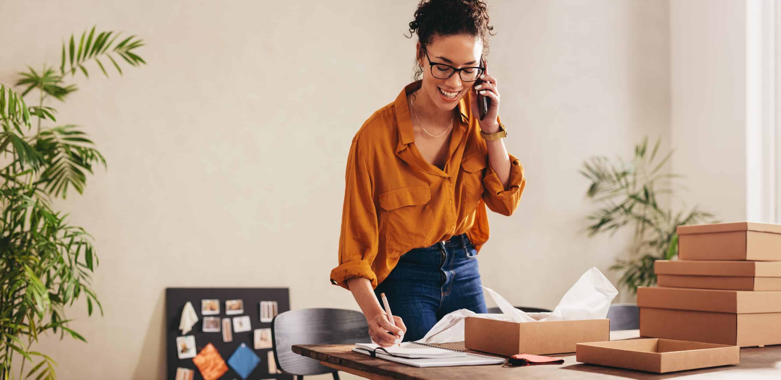 Start-up founder in office space to rent bicester taking a phone call and making notes at the desk