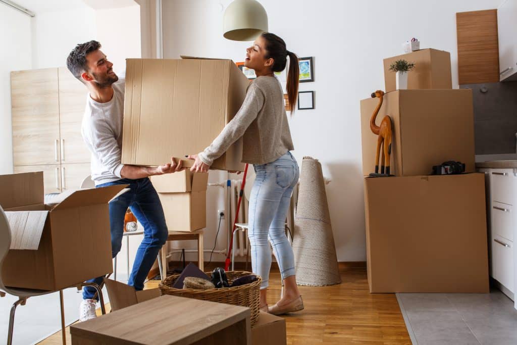 house move storage Enfield - photograph shows a couple holding a packed up moving box between them, with the rest of the room packed up in boxes