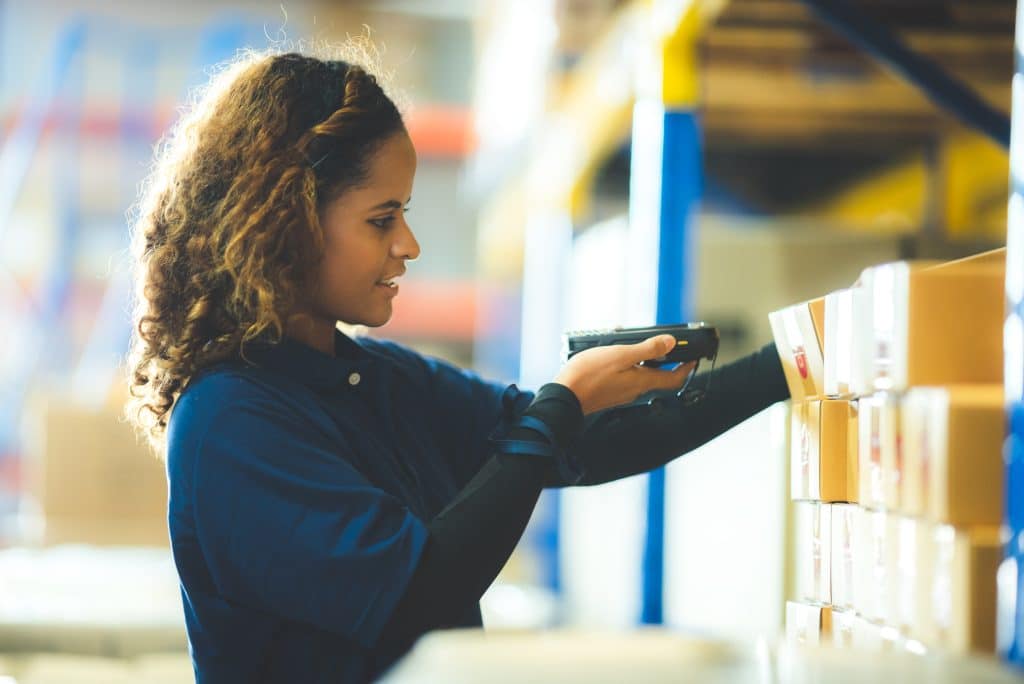 Storage Huntingdon UK - photo shows woman scanning a box of stock with inventory stacked on racking