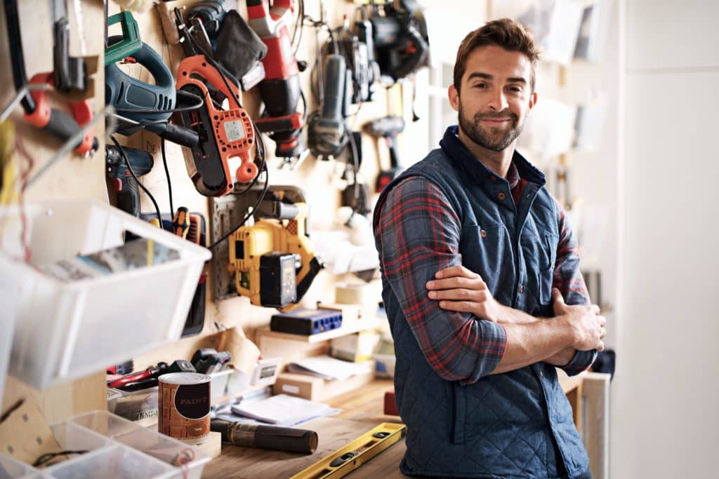 Self storage Bicester - image shows tradesman standing in front of workbench, with his arms folded, with tools hung on the wall and tools on the bench