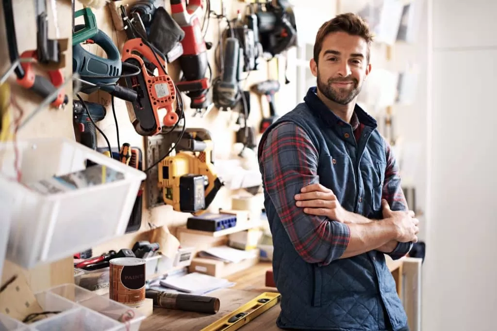 Self storage Bicester - image shows tradesman standing in front of workbench, with his arms folded, with tools hung on the wall and tools on the bench