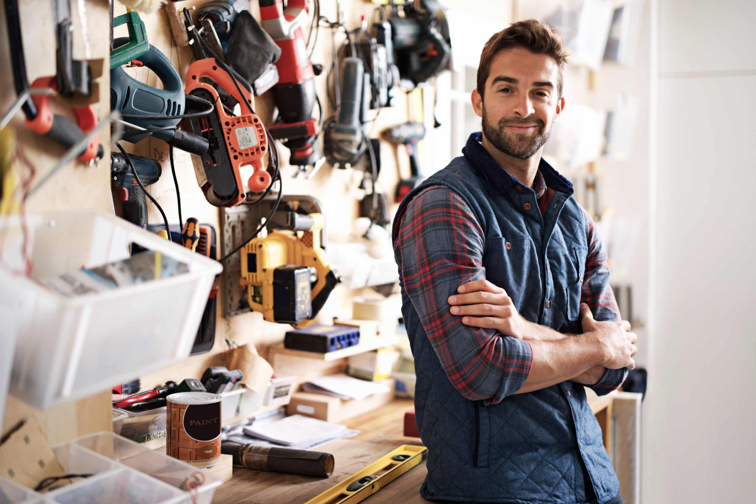 Self storage Bicester Oxfordshire - image shows tradesman standing in front of workbench, with his arms folded, with tools hung on the wall and tools on the bench