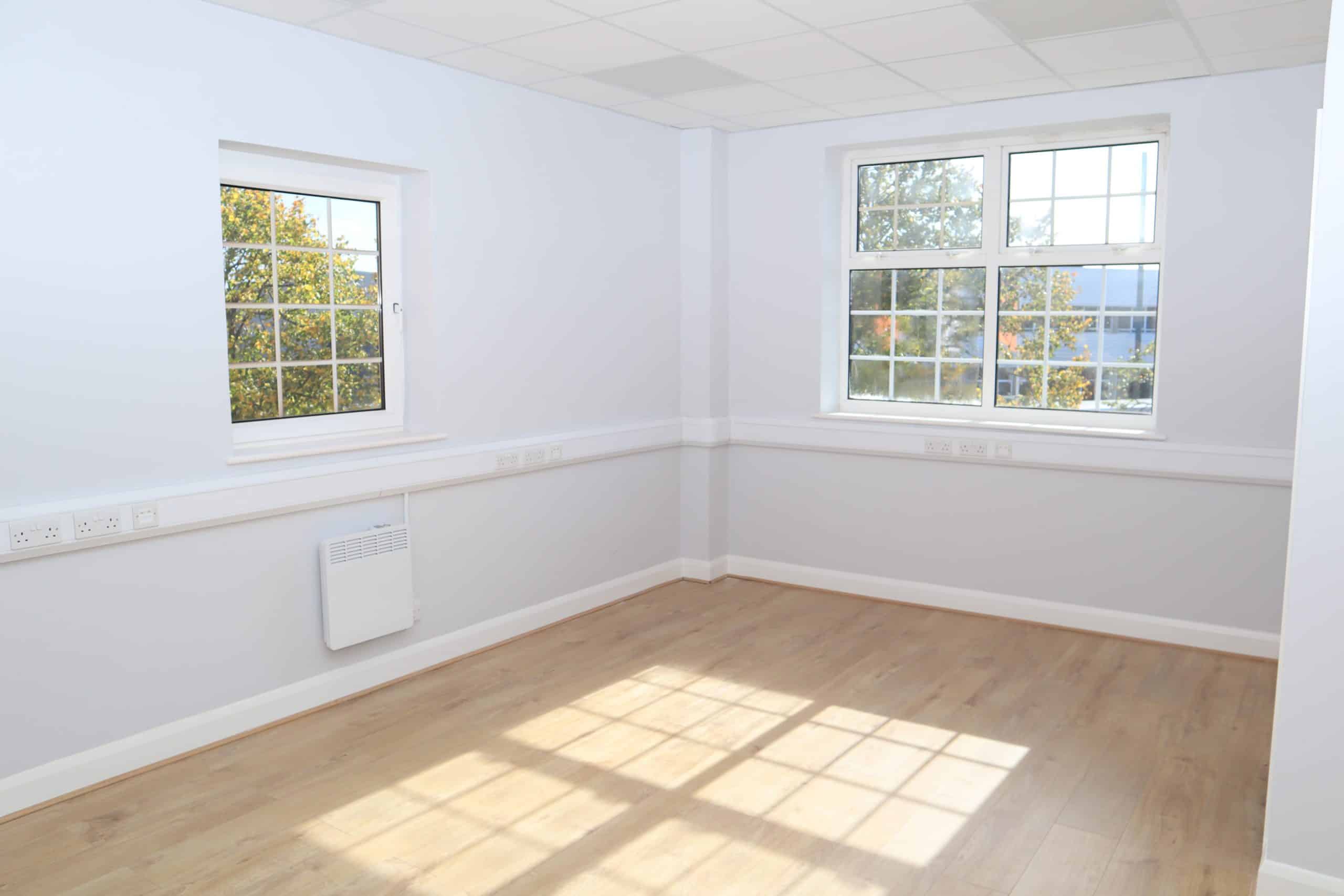 Chippenham Office Space: Start your business in this vibrant West Country town. Image shows an empty office space with double windows and light brown floor with sunlight flooding in.