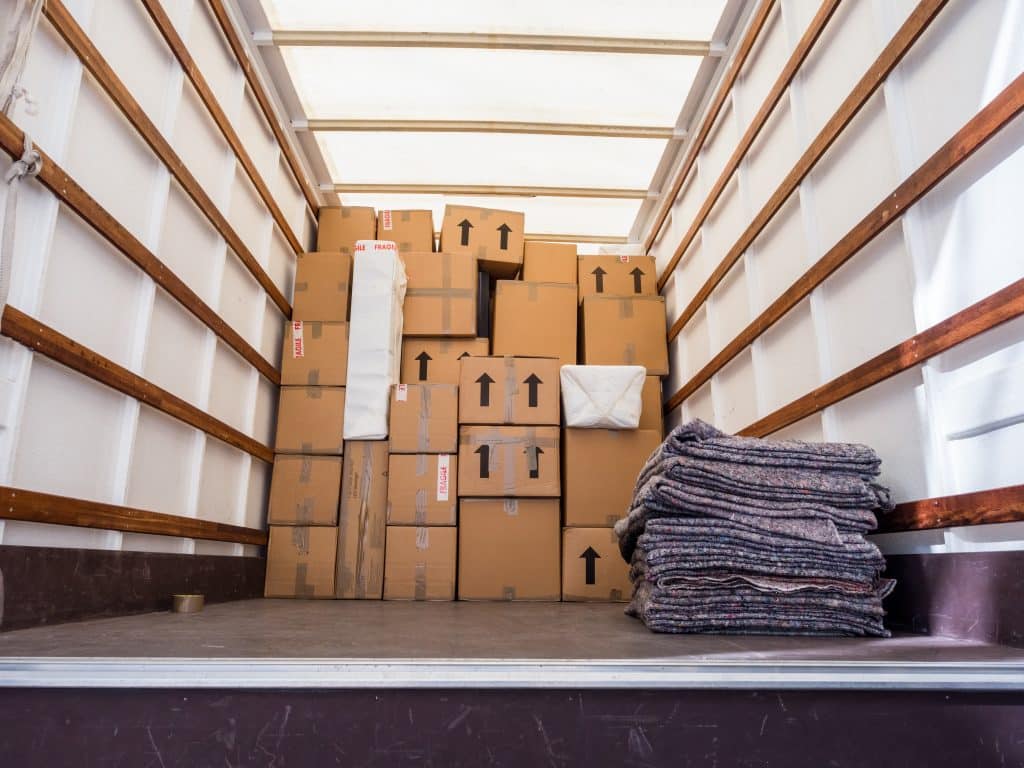 House move storage Gillingham. Image shows the inside of a removal van filled with cardboard boxes and a pile of removal blankets 