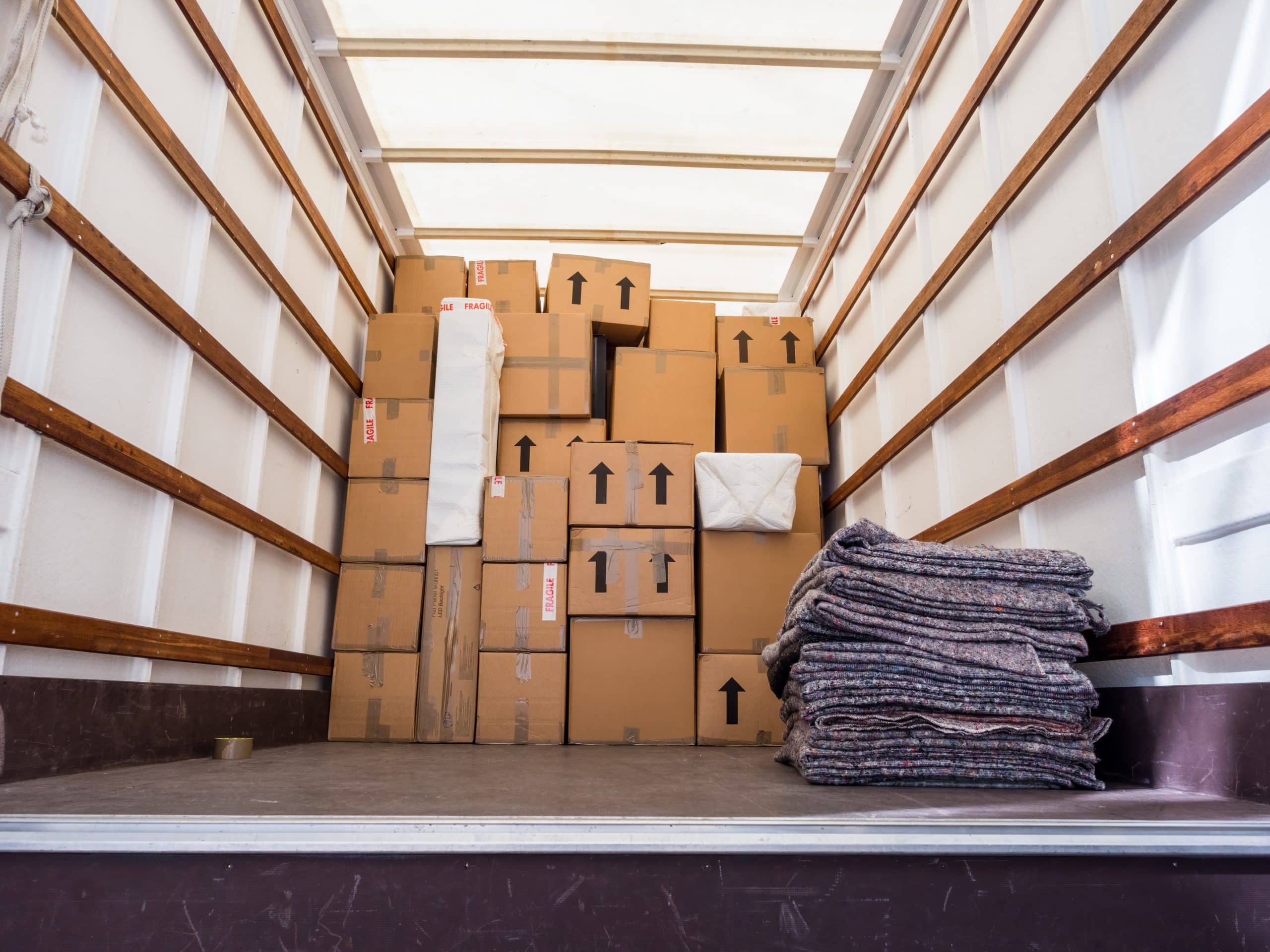 House move storage Gillingham. Image shows the inside of a removal van filled with cardboard boxes and a pile of removal blankets