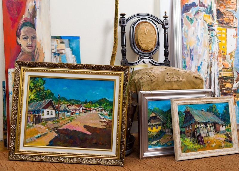 Self-storage Newbury. Image shows the interior of a storage room with paintings on the floor and an antique chair in the background