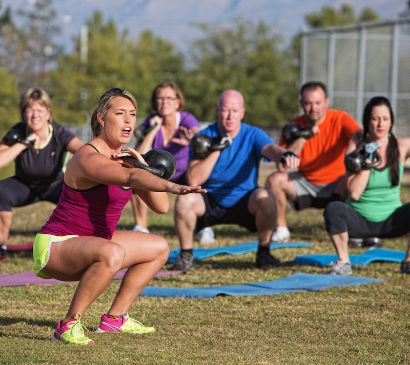 Storage unit Brentwood. Image shows an outdoor exercise bootcamp class with the female instructor in the foreground and the class in the background holding kettlebells