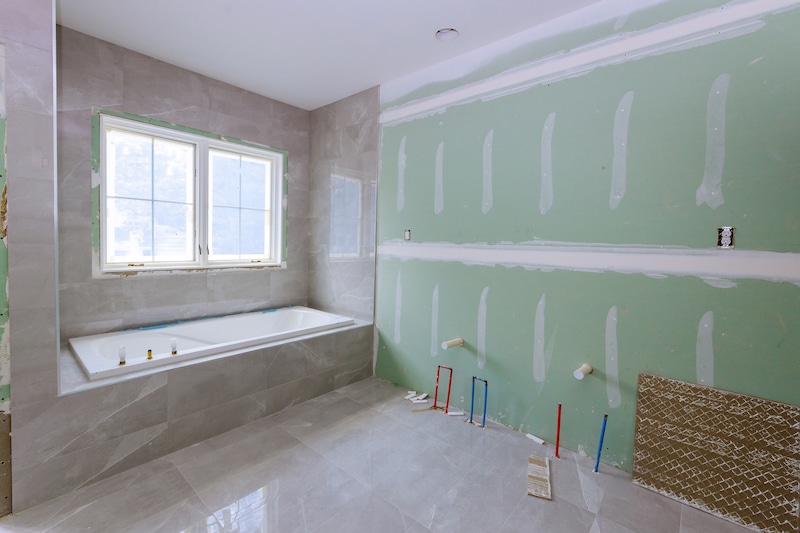 Storage unit to rent Mitcham. Image shows a bathroom being renovated with tiling on the floor and aroudn the bath, but an un-finished wall on the right with plasterboard