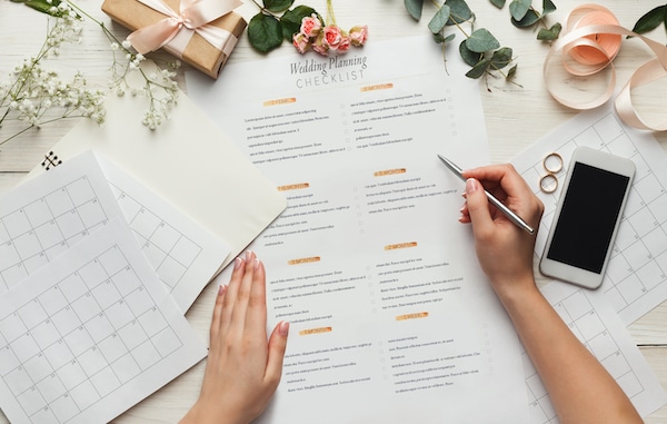 Storage Watford. Image shows a desk covered with wedding planning items including a checklist and calendar. With hands holding a pen 