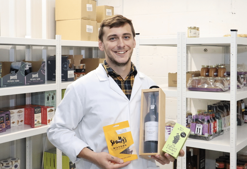 business_storage. Image shows a business customer standing in his storage unit holding his food products surrounded by shelves filled with stock.