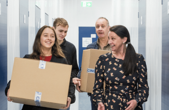 storage_for_students. Image shows daughter, mother and father carrying boxes towards their storage unit. 