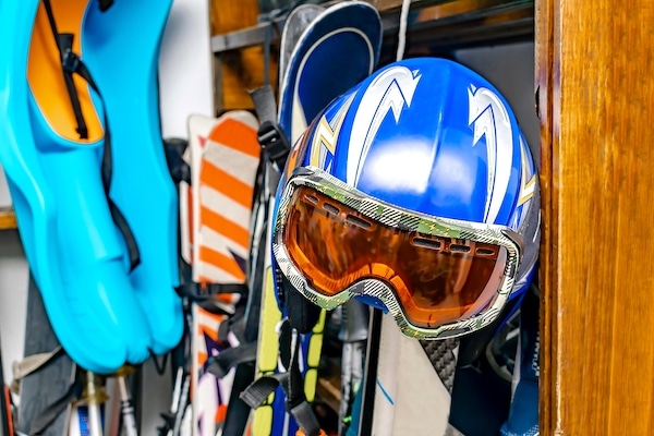 Storing for sports. Image shows a ski helmet, skis, diving flippers and other sports equipment hanging up. 