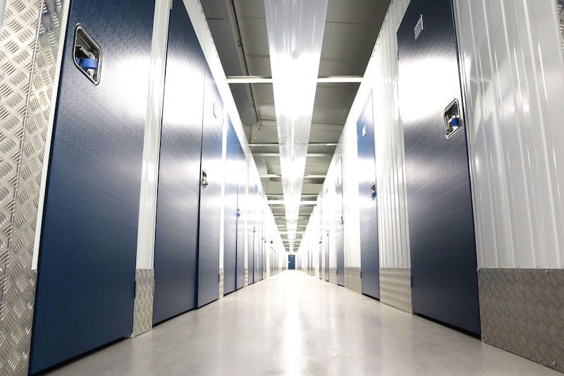 5 key benefits of storage units in Seaford. Image shows corridor of storage units with dark blue doors.