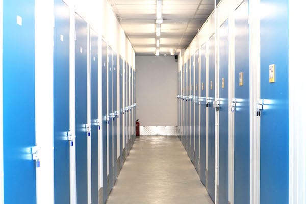 Self storage environmental benefits. Image shows a corridor with blue doors on either side leading to storage units. 