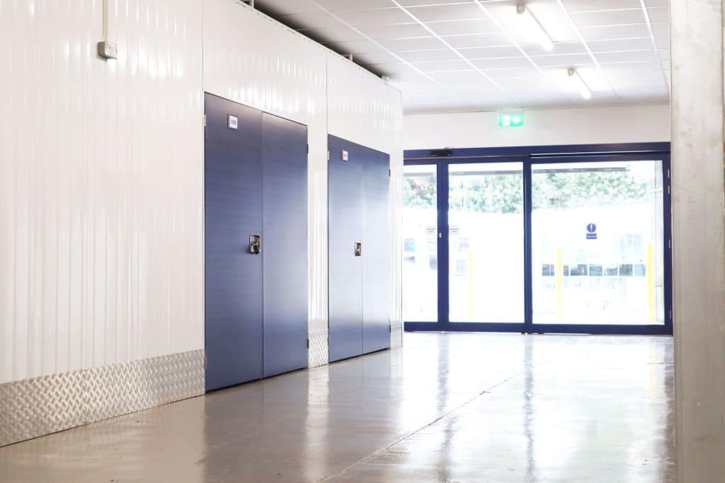 5 reasons to rent a storage unit in Chippenham. Image shows two blue doors to two storage units and a large glass sliding door at the end of the interior. 