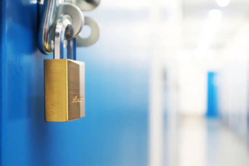 Are Storage Units Safe? A Comprehensive Guide to Storage Unit Security. Image shows a close up view of a padlock on a blue door of a storage unit