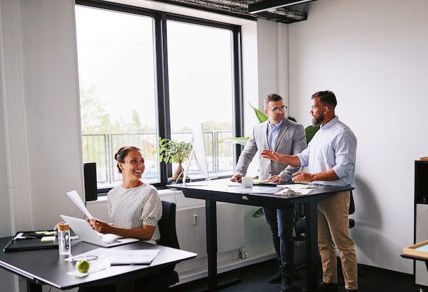 Office to rent in Bicester. Image shows a group of smiling young businesspeople working together at their desks in a small modern office