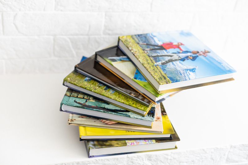 The ultimate guide to photo album storage. Image shows a stack of photo albums in front of a white brick wall