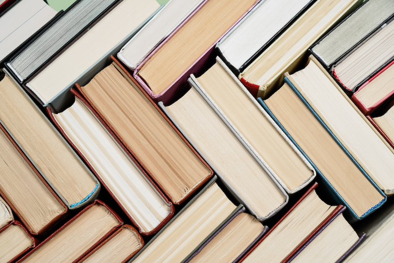 6 Tips for long term book storage. Image shows a herringbone pattern of books.