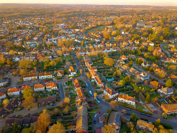 Is Woking a nice place to live? Image shows an aerial view of suburban housing with trees at sunset