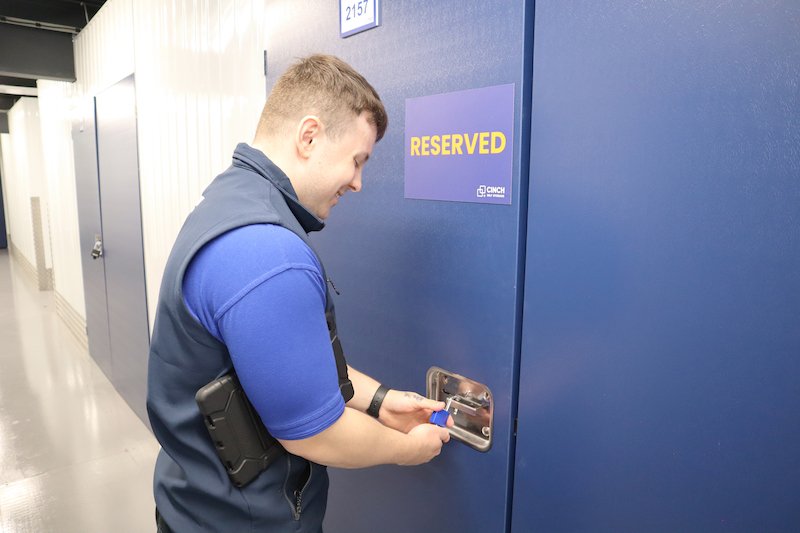 Low cost storage Swindon. Image shows a Cinch Self Storage employee padlocking a unit that has a reserved sign on it.