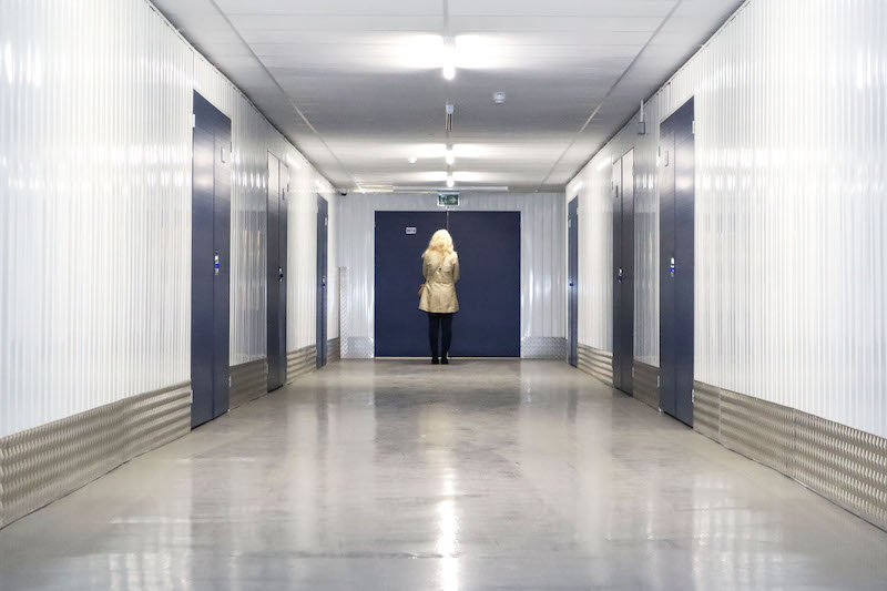 Newmarket storage. image shows a woman walking towards the blue door of a storage unit.