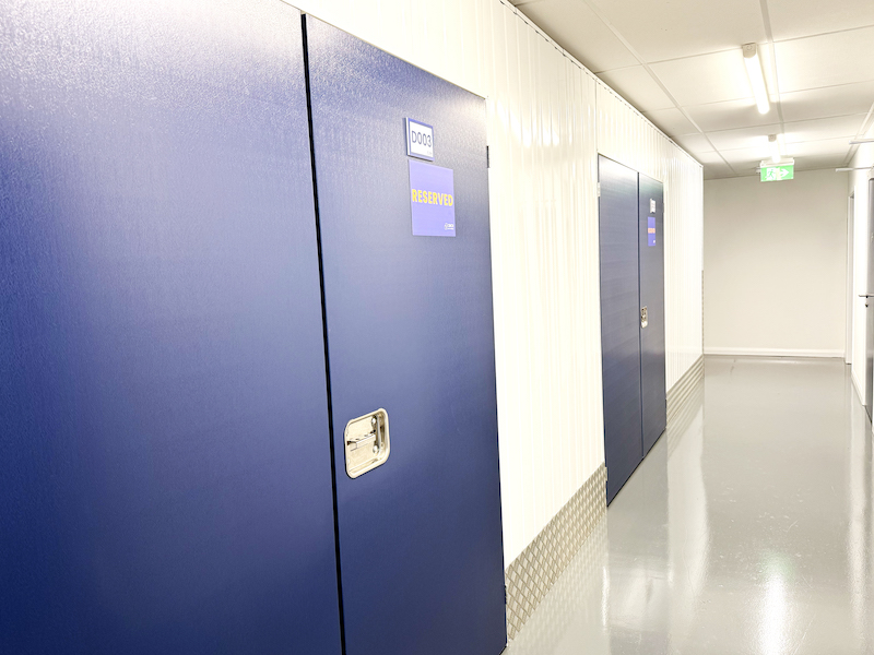 Storage unit in Bedfordshire. Image shows the internal corridor of a storage unit facility with a blue door of a storage unit and a reserved sign on it.